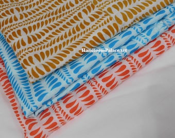 May include: Three pieces of fabric with a white background and a repeating pattern of teardrop shapes. The fabric is layered, with the top layer being a light brown color, the middle layer being a light blue color, and the bottom layer being a light orange color.