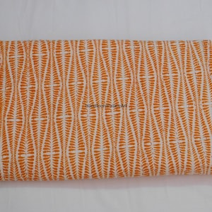 K&ouml;nnte beinhalten: Orangefarbener und wei&szlig;er Baumwollstoff mit einem sich wiederholenden Muster aus kleinen, gekr&uuml;mmten Linien. Der Stoff ist in der Mitte gefaltet und der Text "HandloomPalaceArt" ist sichtbar.