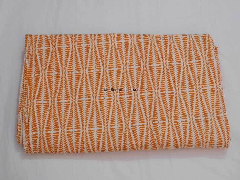 K&ouml;nnte beinhalten: Orangefarbener und wei&szlig;er Baumwollstoff mit einem sich wiederholenden Muster aus kleinen, gekr&uuml;mmten Linien. Der Stoff ist in der Mitte gefaltet und der Text "HandloomPalaceArt" ist sichtbar.