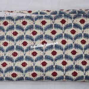 Puede incluir: Una tela doblada con fondo blanco y un patr&oacute;n repetitivo de hojas azules y flores rojas. La tela tiene una textura de tejido a mano y es ideal para acolchar o proyectos de artesan&iacute;a.