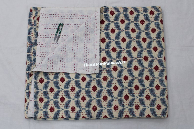 Puede incluir: Una colcha kantha de algod&oacute;n blanco con un patr&oacute;n floral azul y rojo. La colcha est&aacute; cosida a mano y tiene un dise&ntilde;o tradicional indio. "HandloomPalaceArt" est&aacute; impreso en la colcha.