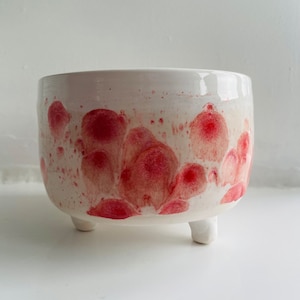 May include: White ceramic planter with three legs and a red and white abstract design.
