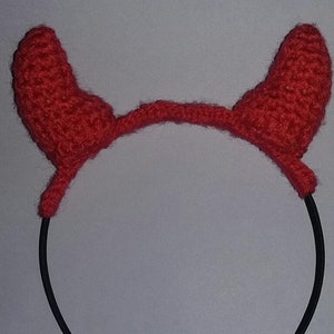 Peut inclure: Un serre-tête avec des cornes de diable rouges crochetées. Les cornes sont d'un rouge vif et fixées à un serre-tête en plastique noir. Les cornes sont arrondies et texturées, ce qui leur donne un aspect doux. Cet accessoire convient aux costumes ou aux événements à thème.