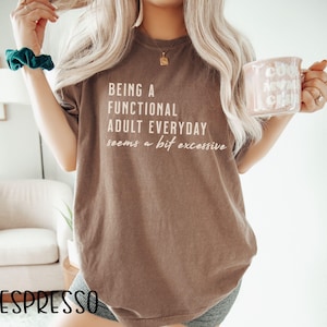 May include: A brown t-shirt with the text "Being a functional adult everyday seems a bit excessive" printed on it.