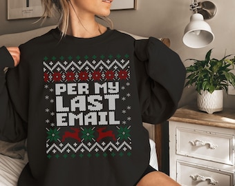 Op de afbeelding: Zwart sweatshirt met een feestelijk ontwerp. Het ontwerp bevat de tekst "PER MY LAST EMAIL" in witte blokletters, omringd door sneeuwvlokken, rendieren en geometrische patronen in rood, groen en wit. Een comfortabele, casual top.