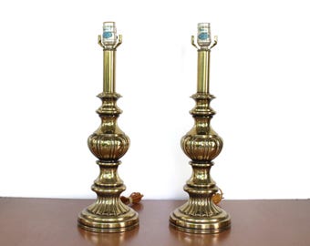 May include: A pair of gold-toned table lamps with a fluted design. The lamps have a classic, traditional style.