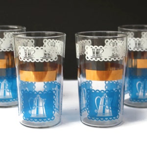 May include: Set of four vintage glass tumblers with a blue and white design. The glasses feature a gold band and a repeating pattern of a coffee pot with a white lace border.