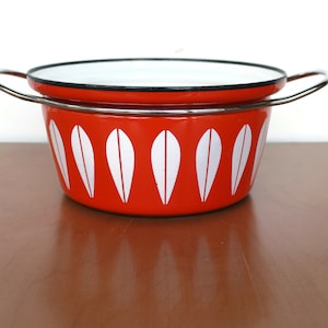 Könnte beinhalten: Roter Emailtopf mit weißem Blattdesign und einem silbernen Deckelgriff.