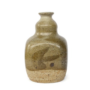 Könnte beinhalten: Eine braune Keramikvase mit einer strukturierten Oberfläche und einem einzigartigen Design. Die Vase hat einen breiten Boden und einen schmalen Hals.