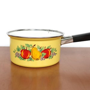 Puede incluir: Cacerola de esmalte amarilla con mango negro y un diseño floral con peras, manzanas y bayas.