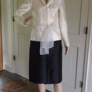 Collectie Preveé Haute Couture Paris Tweedelig zijden pak crème kleur jas met zwarte emboidere bloem en zwarte zijden rok.