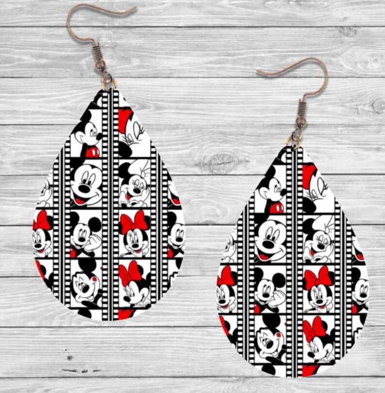 Op de afbeelding: Een paar druppelvormige oorbellen met een zwart-wit filmstripontwerp. De oorbellen tonen afbeeldingen van Mickey en Minnie Mouse met rode accenten en strikken. Ze hebben bronzen oorhaken.