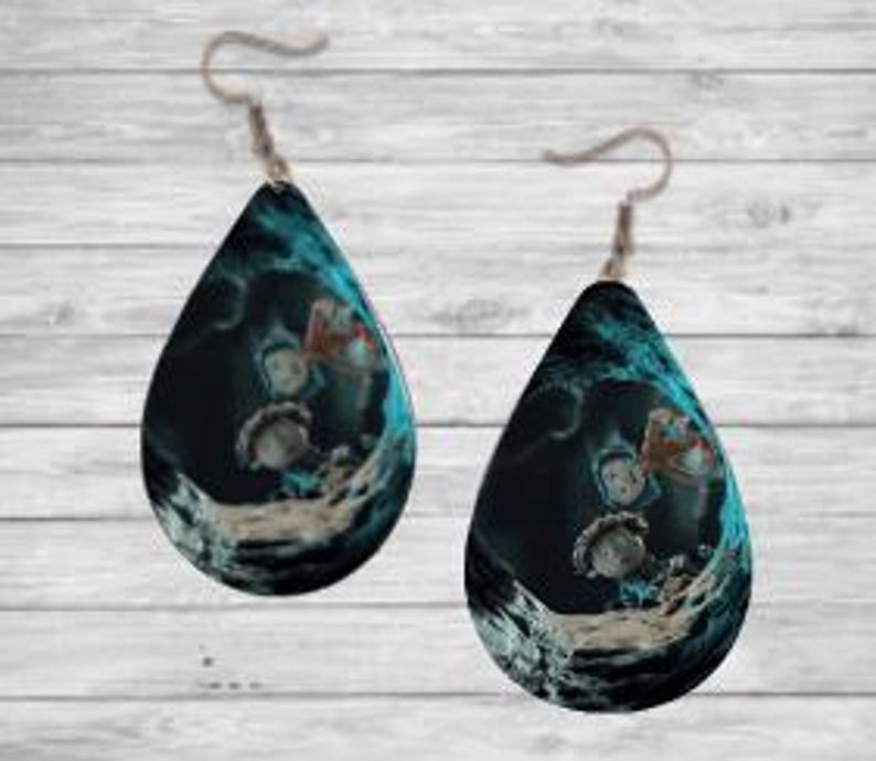 Peut inclure: Une paire de boucles d'oreilles en forme de goutte d'eau avec un motif bleu fonc&eacute; et sarcelle. Les boucles d'oreilles pr&eacute;sentent une illustration fantaisiste de personnages dans un cadre fantastique. Elles sont suspendues &agrave; des crochets d'oreilles argent&eacute;s.