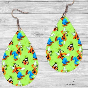 Op de afbeelding: Druppelvormige oorbellen met een groene achtergrond met een patroon van een stripfiguur in oranje, blauw en wit. De oorbellen hebben een koperkleurige haak.