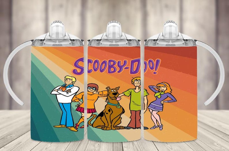 K&ouml;nnte beinhalten: Drei Trinkbecher mit den Scooby-Doo-Zeichentrickfiguren. Jeder Becher hat ein farbenfrohes Design mit den Figuren und dem Logo der Show. Der Hintergrund hat ein Retro-Regenbogen-Streifen-Design.