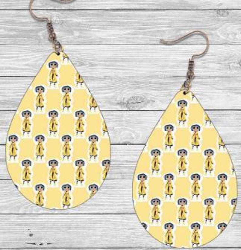 Peut inclure: Boucles d'oreilles en forme de goutte d'eau avec un fond jaune et un motif r&eacute;p&eacute;t&eacute; d'un personnage de dessin anim&eacute; en imperm&eacute;able jaune. Fermeture &agrave; crochet, finition m&eacute;tal marron clair.