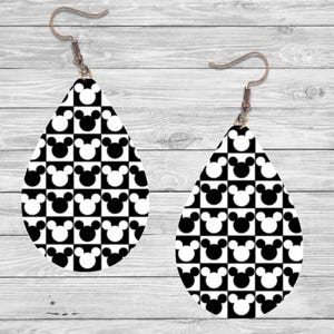 Op de afbeelding: Een paar druppelvormige oorbellen met een zwart-wit geblokt patroon met Mickey Mouse-silhouetten. De oorbellen hebben bronzen oorhaken. Het ontwerp is een speels en herkenbaar patroon.