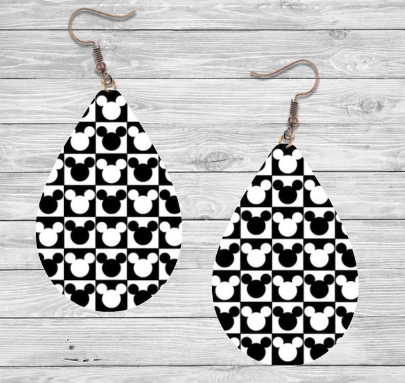 Op de afbeelding: Een paar druppelvormige oorbellen met een zwart-wit geblokt patroon met Mickey Mouse-silhouetten. De oorbellen hebben bronzen oorhaken. Het ontwerp is een speels en herkenbaar patroon.
