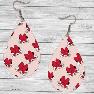 Op de afbeelding: Druppelvormige oorbellen met een lichtroze achtergrond en een herhalend patroon van Minnie Mouse-gezichten met rode strikken. De oorbellen hebben bronzen oorhaken.