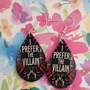 Peut inclure: Paire de boucles d'oreilles en forme de goutte d'eau avec le texte "I PREFER THE VILLAIN" en blanc. Les boucles d'oreilles noires présentent des roses rouges et des éléments décoratifs. Crochets d'oreilles argentés.