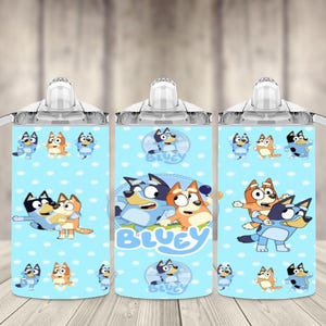 K&ouml;nnte beinhalten: Drei hellblaue Trinkbecher mit wei&szlig;en Griffen und Deckeln. Jeder Becher zeigt ein Cartoon-Design von Bluey-Charakteren mit dem Wort "Bluey" in Wei&szlig;. Die Becher haben ein hellblaues Tupfenmuster.