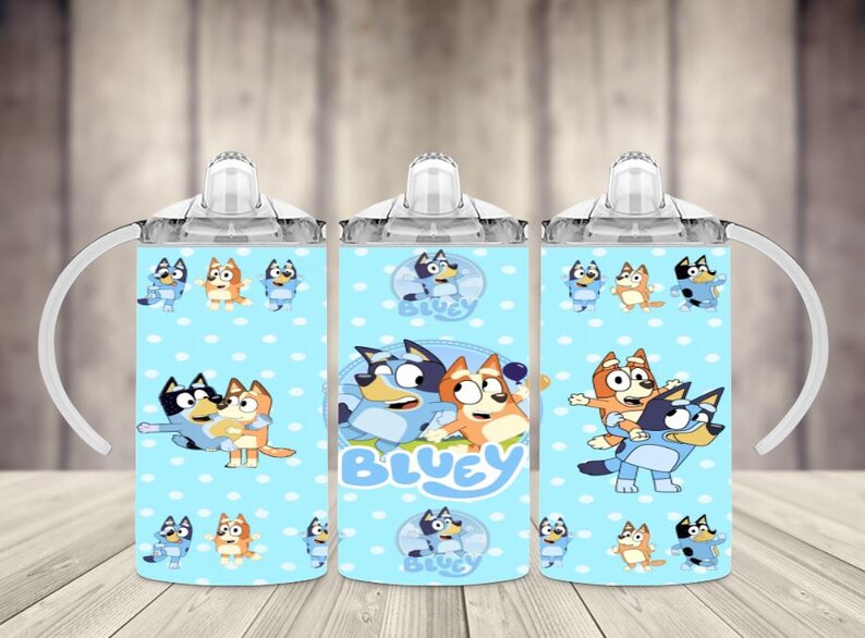 K&ouml;nnte beinhalten: Drei hellblaue Trinkbecher mit wei&szlig;en Griffen und Deckeln. Jeder Becher zeigt ein Cartoon-Design von Bluey-Charakteren mit dem Wort "Bluey" in Wei&szlig;. Die Becher haben ein hellblaues Tupfenmuster.