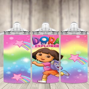 K&ouml;nnte beinhalten: Ein Trinkbecher f&uuml;r Kinder mit Dora der Entdeckerin. Der Becher hat einen rosa, blauen und gelben Hintergrund mit Sternen und Regenb&ouml;gen. Dora ist in der Mitte abgebildet, tr&auml;gt ein rosa Hemd und orangefarbene Shorts. Er hat einen wei&szlig;en Griff und Deckel.
