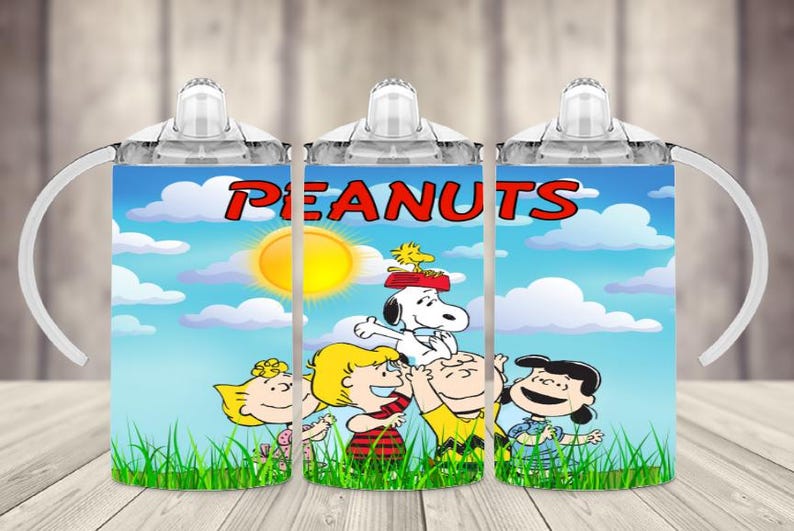 K&ouml;nnte beinhalten: Drei Trinkbecher mit einem farbenfrohen Design mit dem Wort "PEANUTS" in Rot. Die Becher zeigen Snoopy, Woodstock und andere Peanuts-Charaktere vor einem blauen Himmel mit Sonne und Wolken. Jeder Becher hat einen wei&szlig;en Griff.