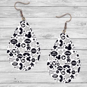 Op de afbeelding: Een paar druppelvormige oorbellen met een zwart-wit Mickey Mouse-ontwerp. De oorbellen hebben verschillende Mickey Mouse-thema's, waaronder sterren, tekstballonnen en de woorden "Mickey Mouse" en "Cheese Cheese". De oorbellen hebben bronzen oorhaken.