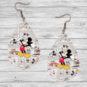 Op de afbeelding: Een paar druppelvormige oorbellen met een vintage Mickey Mouse stripontwerp. De oorbellen tonen Mickey in zijn rode broek, gele schoenen en witte handschoenen, tegen een zwart-witte stripachtergrond.