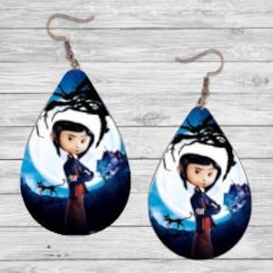 Peut inclure: Paire de boucles d'oreilles en forme de goutte d'eau avec un personnage de dessin anim&eacute; devant une pleine lune, un chat noir et une toile d'araign&eacute;e. Les boucles d'oreilles ont des crochets d'oreille argent&eacute;s et un fond bleu et noir.