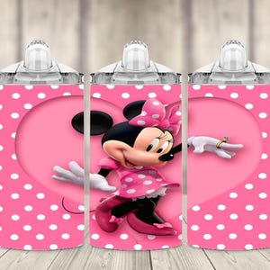 K&ouml;nnte beinhalten: Ein rosa Trinkbecher mit wei&szlig;em Polka-Dot-Muster und Minnie-Maus-Design. Der Becher hat einen rosa herzf&ouml;rmigen Hintergrund und ein Cartoon-Bild von Minnie Maus in einem rosa Kleid und einer Schleife.
