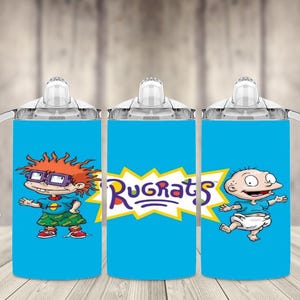 K&ouml;nnte beinhalten: Drei blaue Trinkbecher mit wei&szlig;en Griffen und Deckeln, die Charaktere aus der Zeichentrickserie Rugrats zeigen. Die Becher zeigen Bilder von Chuckie, Tommy und dem Rugrats-Logo.