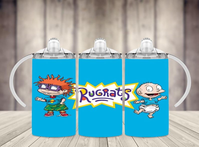 K&ouml;nnte beinhalten: Drei blaue Trinkbecher mit wei&szlig;en Griffen und Deckeln, die Charaktere aus der Zeichentrickserie Rugrats zeigen. Die Becher zeigen Bilder von Chuckie, Tommy und dem Rugrats-Logo.