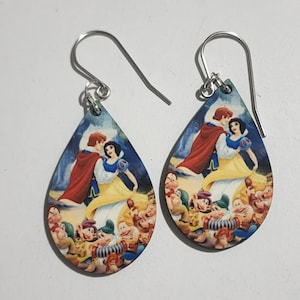 May include: A pair of teardrop-shaped earrings with a colorful image of Snow White and the Seven Dwarfs. The earrings are made of wood and have silver hooks.