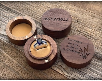 May include: Three wooden ring boxes. One box has a blue ring with a diamond inside. One box has the date 09/17/2022 engraved on it. The third box has the text "You must be my once in a lifetime" engraved on it.