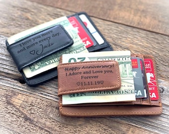 May include: Two leather wallets with engraved messages. The top wallet is black and says "I love you more and more every day. Jacki". The bottom wallet is brown and says "Happy Anniversary! I Adore and Love you, Forever 11.11.19".