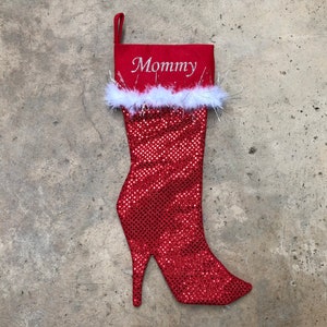 May include: Red sparkly Christmas stocking shaped like a high heel shoe with a white faux fur trim and the word "Mommy" embroidered on the front.