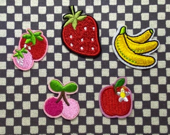 Puede incluir: Cinco parches bordados para planchar con diseños de frutas. Los parches son una fresa, un plátano, una cereza, una manzana y una fresa con un tallo y hojas verdes.