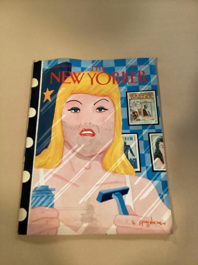 May include: The New Yorker magazine cover features a woman with blonde hair looking in a mirror, holding a razor and a can of shaving cream. The background is a blue and white checkered pattern. The text "The New Yorker" is printed in black at the top of the cover.