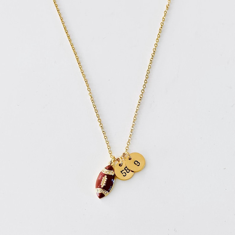 May include: Gold chain necklace with a small football charm and two round charms with the numbers 58 and 9.
