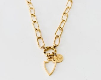 Puede incluir: Un collar de cadena dorada con un pequeño dije de flecha dorada y un dije de disco dorado con las iniciales "KC" grabadas.