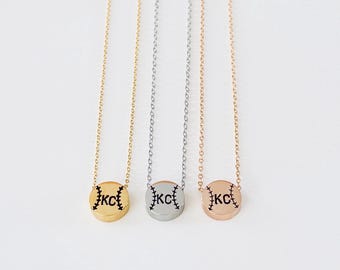 Puede incluir: Tres collares con colgantes con temática de béisbol en oro, plata y oro rosa. Cada colgante es un disco con costuras negras y las letras "KC". Los collares cuelgan de finas cadenas.