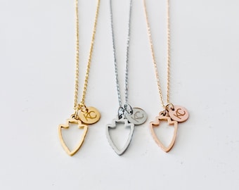 Puede incluir: Tres delicados collares con colgantes en forma de flecha y pequeños amuletos redondos. Los collares son dorados, plateados y oro rosa. Cada amuleto tiene las iniciales "KC" grabadas. Las cadenas son finas y los colgantes son huecos.