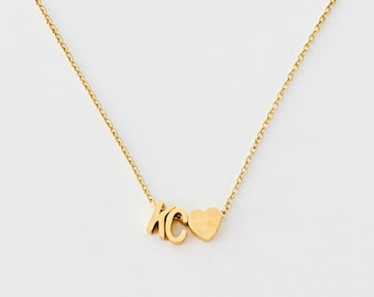 Puede incluir: Un collar de oro con un dije en forma de corazón y las letras "KC".