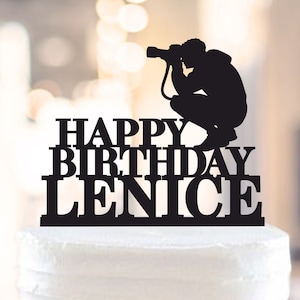 Puede incluir: Topper de pastel en silueta negra de un fotógrafo con una cámara, con el texto "Happy Birthday Lenice" debajo.