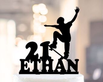 May include: Black silhouette cake topper of a person skateboarding with the number 21 and the name Ethan. The topper is on a white cake.