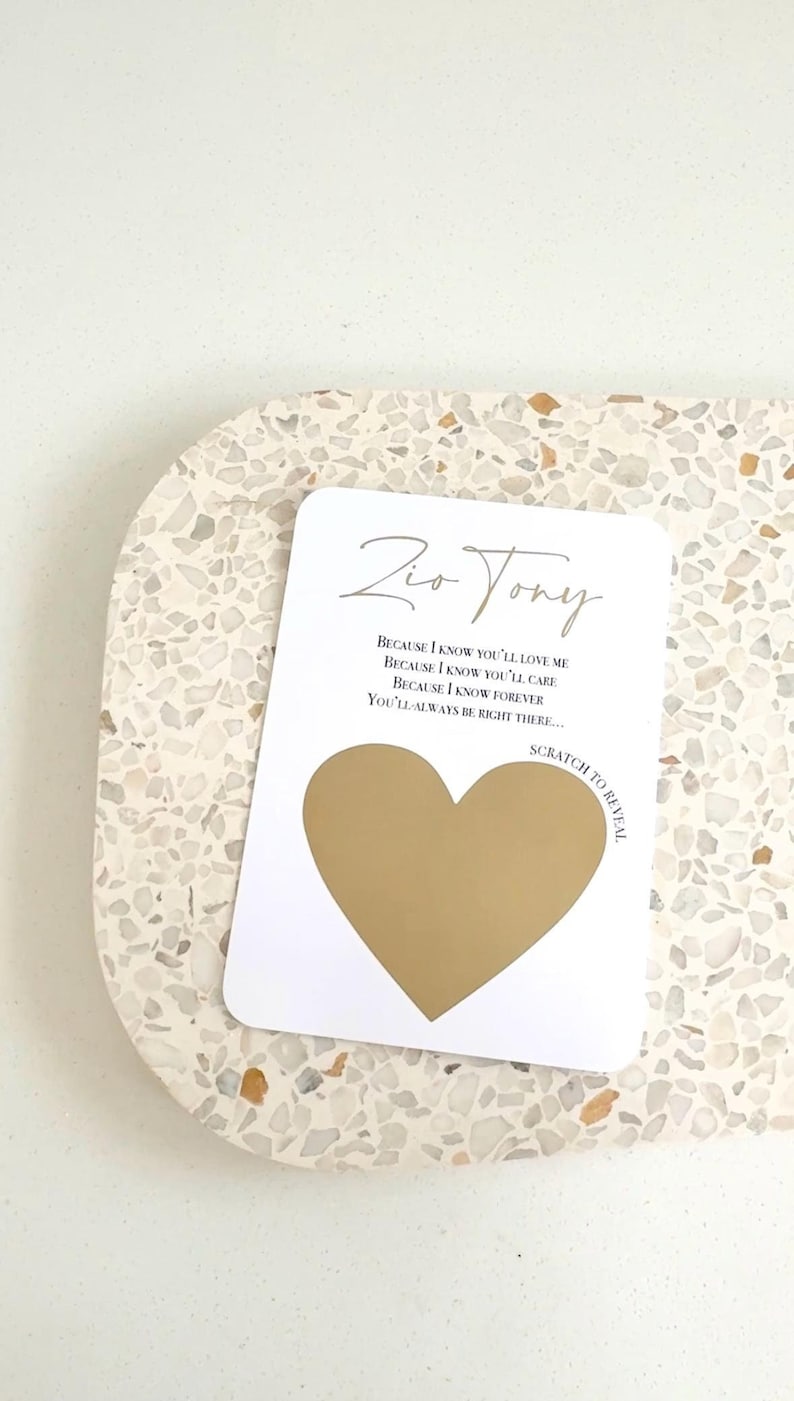 Peut inclure: Une carte blanche avec des lettres dor&eacute;es qui disent "Zio Tony" et "Parce que je sais que tu m'aimeras, Parce que je sais que tu prendras soin de moi, Parce que je sais que pour toujours, Tu seras toujours l&agrave;..." Un c&oelig;ur dor&eacute; est partiellement recouvert d'un rev&ecirc;tement &agrave; gratter. Le texte "Gratter pour r&eacute;v&eacute;ler" est imprim&eacute; sur la carte.