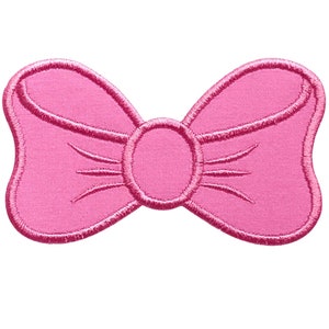 May include: A pink fabric bow with a center loop. The bow is a flat, embroidered patch.