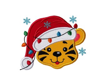 May include: An embroidered patch featuring a yellow tiger face wearing a red and white Santa hat. The design includes a string of colorful Christmas lights wrapped around the hat and several light blue snowflakes surrounding the tiger's head.